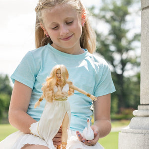 Young girl holding a Venus doll and a swan outdoors