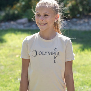 Young girl wearing a 'Olympia Girl' t-shirt outdoors on a sunny day.