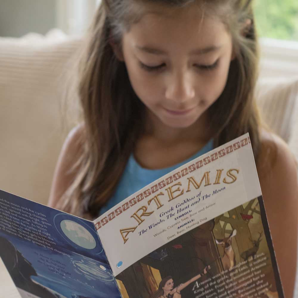 Girl reading a rtemis' Story Card on a couch.
