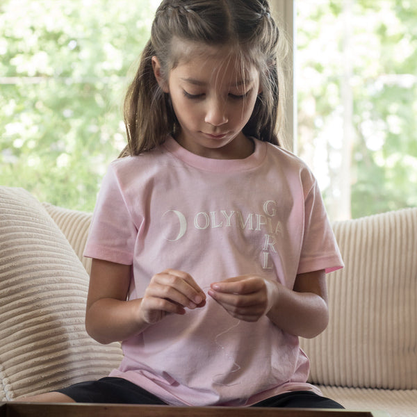 Young girl sitting on a couch with a pink jewelry box and beads.